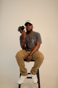 a man sitting on a stool holding a camera